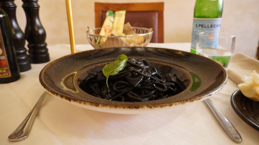 La Piazzaで食べたイカ墨のパスタ。艶やかな黒い麺にバジルを添えて