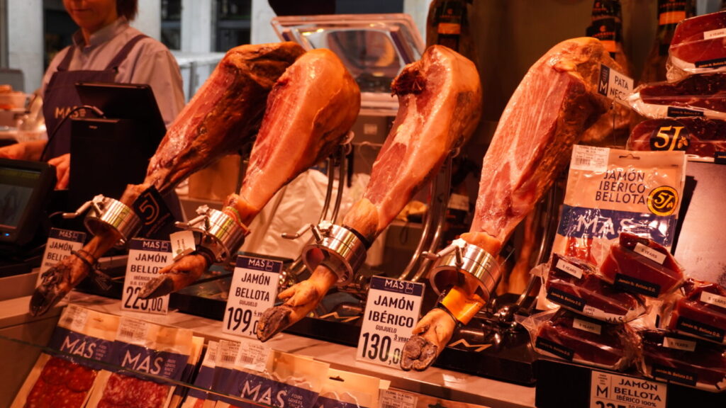 ブケリア市場の精肉店に吊るされた生ハムの脚と値札
